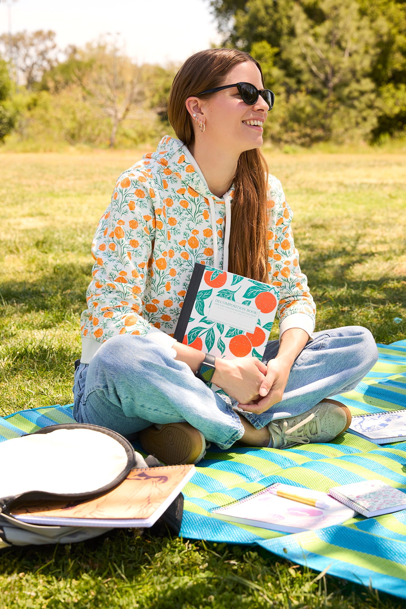 woman on picnic blanket with decomposition books and sweatshirt