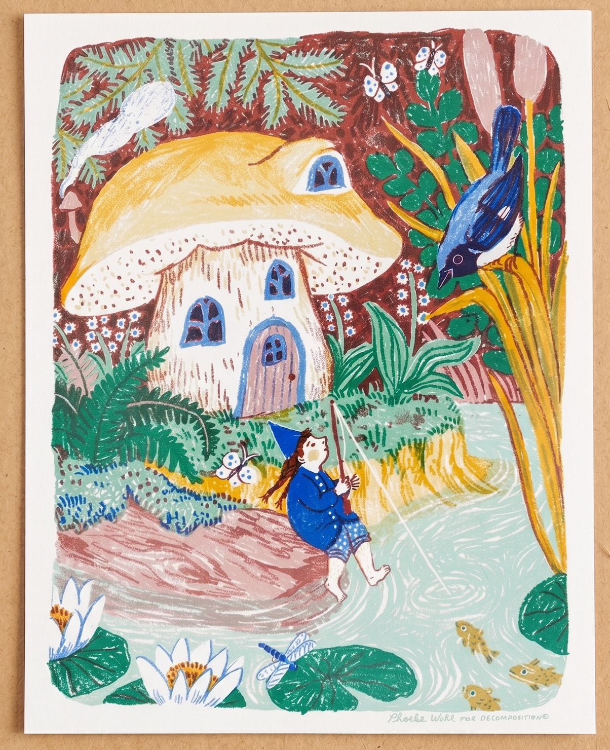 A colorful folk art print depicting a whimsical scene with a child fishing by a pond, a mushroom house, a blue bird, and flowers, shown on a light wood background.