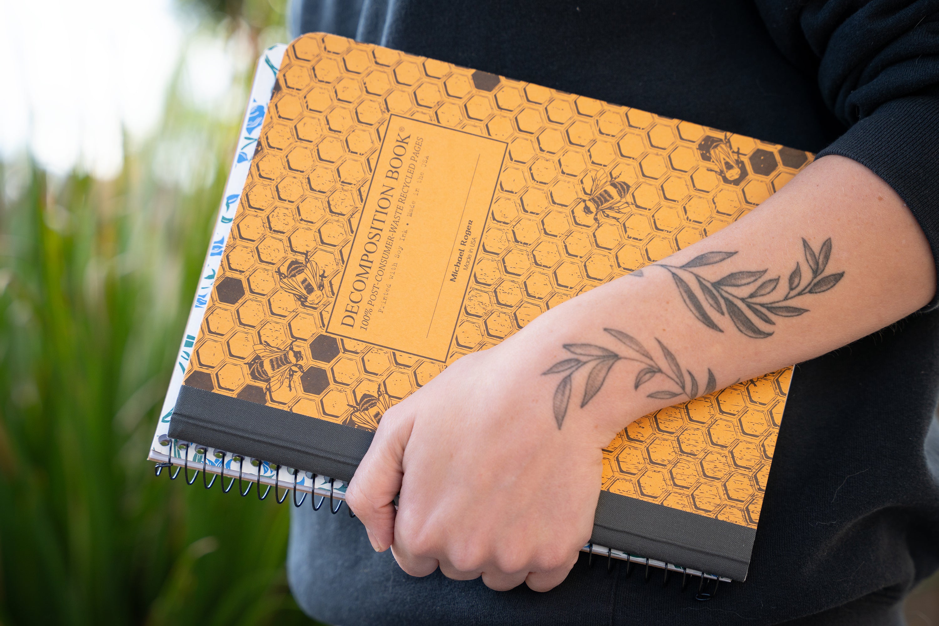 Person's arm holding two notebooks